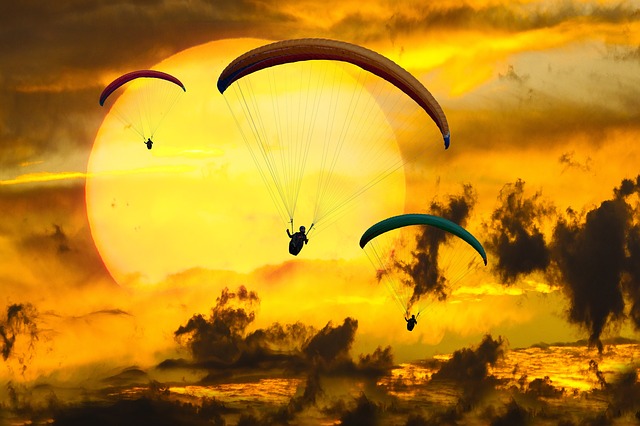 gliding, paragliding, and flying through the air to a sunset